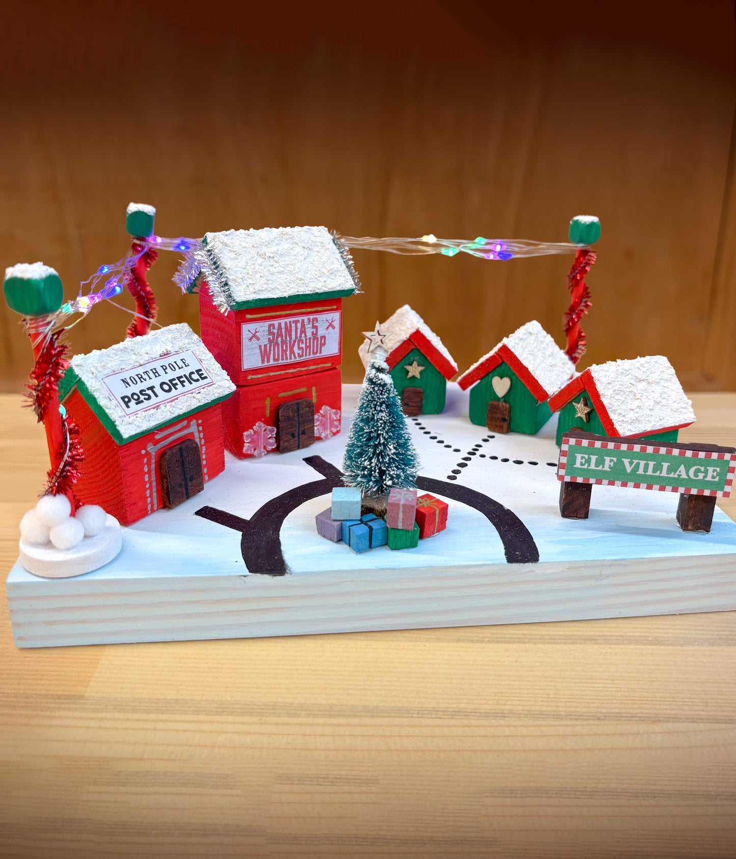 Make your own Elf Village craft kit Christmas-themed model village with buildings and decorations on a wooden surface