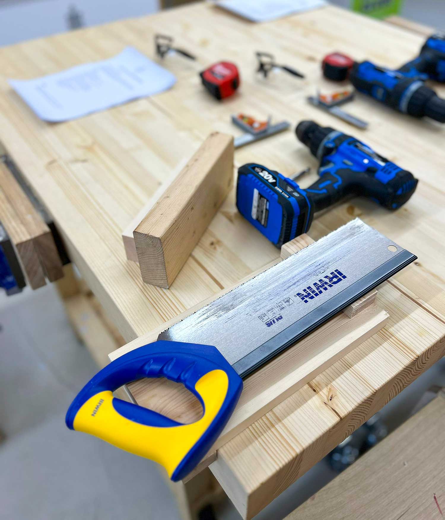 Woodwork hand tools including a saw and electric screwdriver on a wooden workbench in Ash and Co Workshops